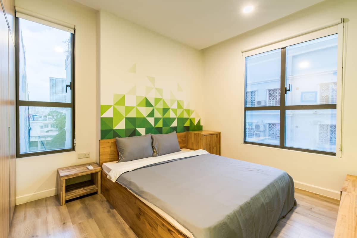 Un dormitorio moderno con una cama, cabecera de madera y un diseño geométrico en la pared.