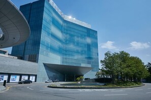 A modern building with a curved glass facade and a prominent overhang.