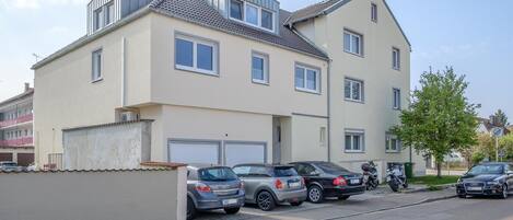 A multi-story residential building with a garage and a parking area.