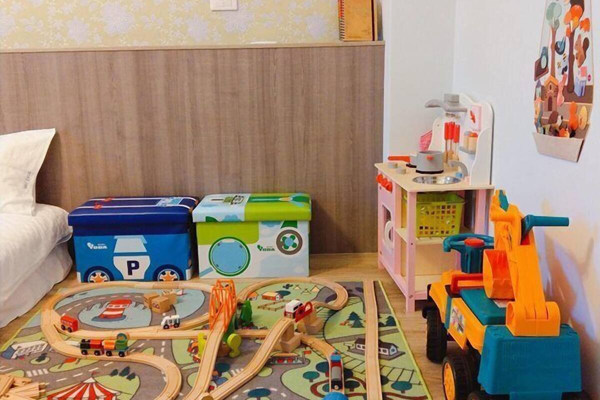 A child's playroom with a train set, storage boxes, and a toy excavator.