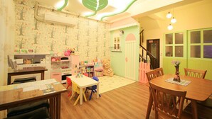 A children's playroom with a wooden table, colorful chairs, and a teddy bear. - Mi Casa Bed and Breakfast (Taitung)