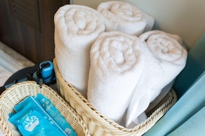 A basket of neatly rolled white towels, a blue travel card, and a wicker basket. - Mi Casa Bed and Breakfast (Taitung)