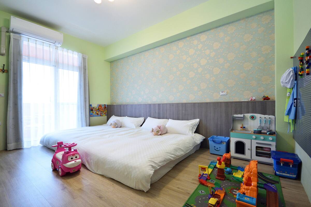 A bedroom with a bed, a toy car, and a play kitchen set.