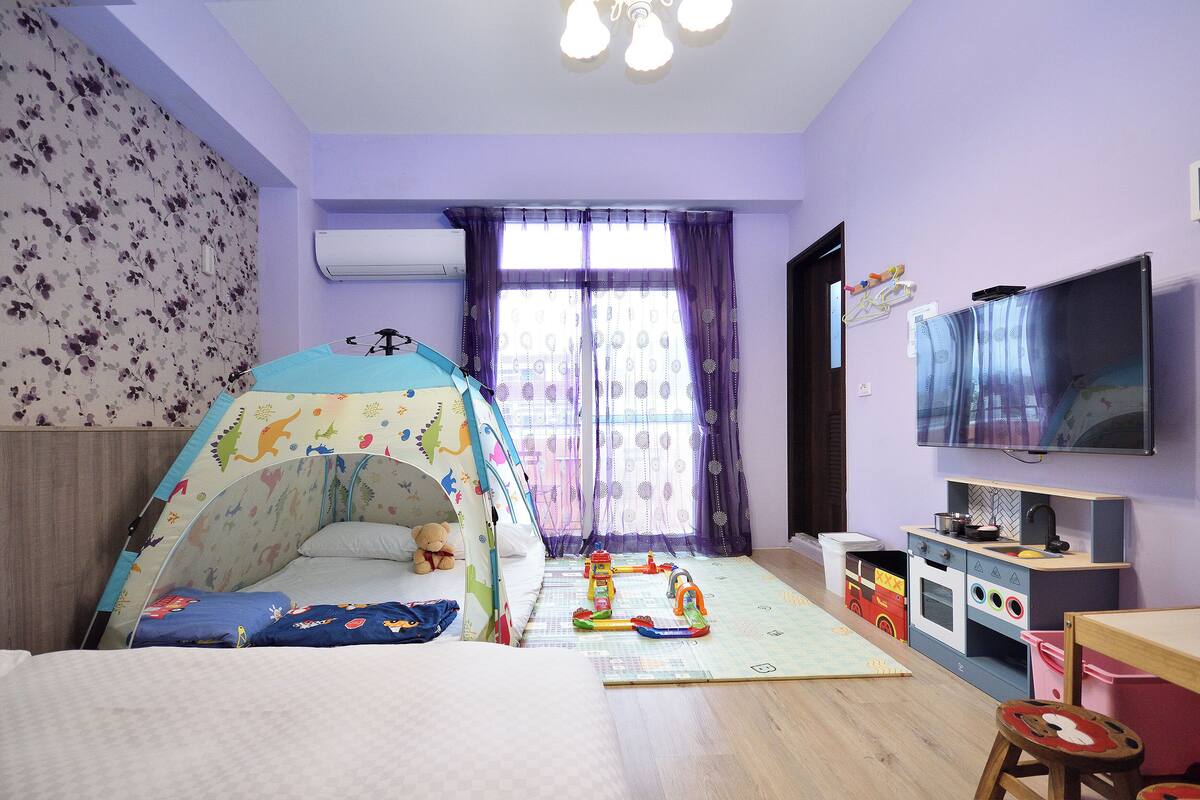 A child's playroom with a bed, play tent, play kitchen, and a TV.