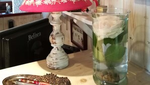 Ett bord med en röd lampa, ett glas som innehåller stenar och en växt, och ett bricka med cigaretter och en tändare.