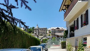 En bostadsgata med parkerade bilar, en kyrka och hus med balkonger.