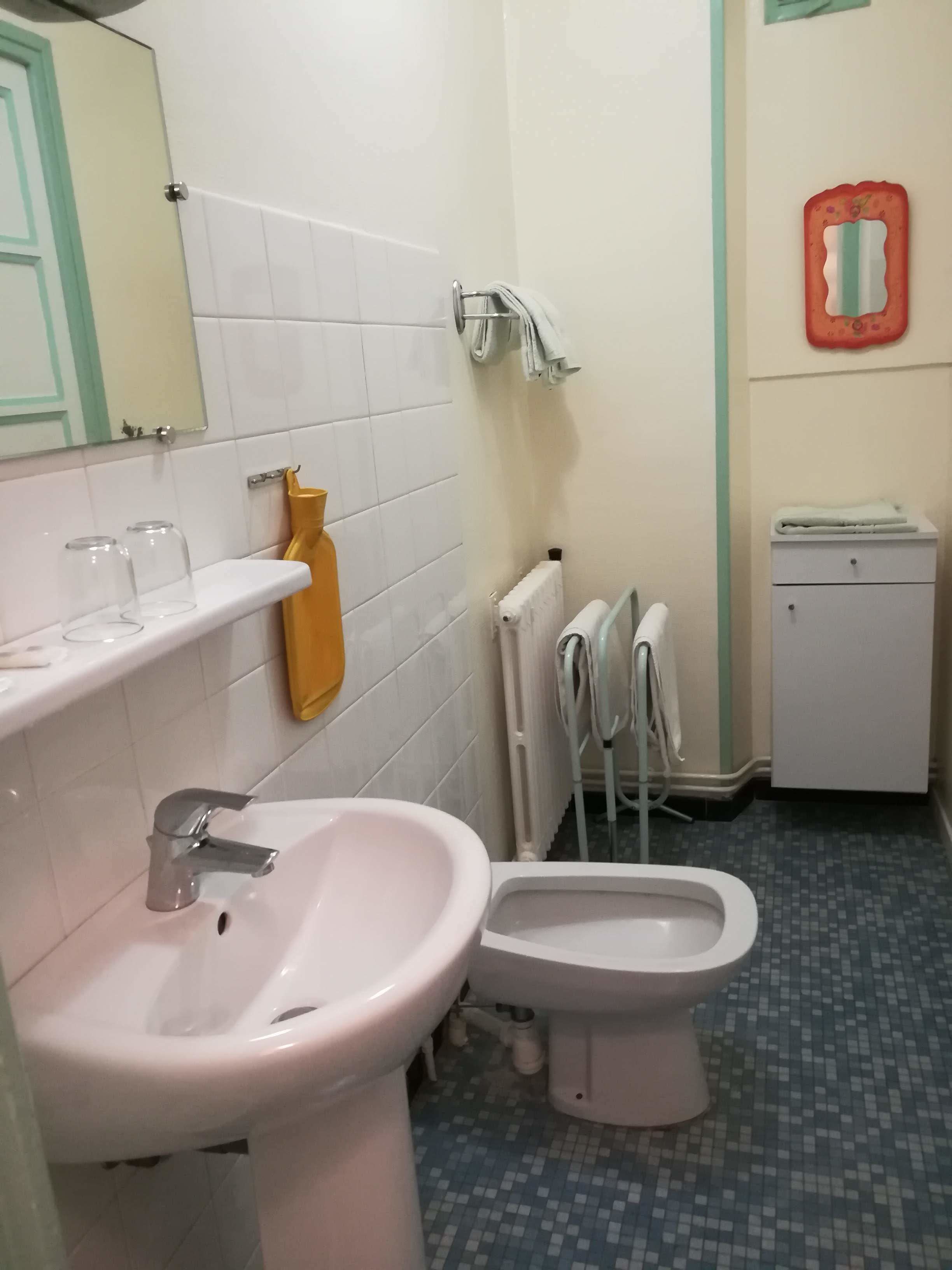 Een badkamer met een wastafel, toilet en een klein kastje.