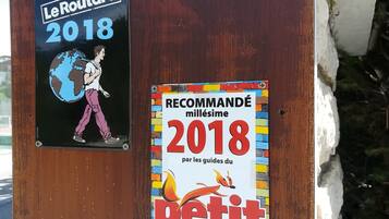Dois cartazes fixados numa tábua de madeira desgastada, um para Le Routard 2018 e outro para a coleção Millesime Petit Fute de 2018.