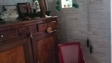 A wooden dresser with a mirror, a red chair, and wall-mounted decorations including a clock and a framed picture.