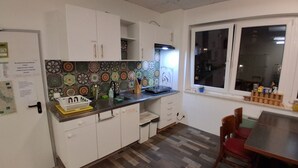 A compact kitchen with white cabinets, a patterned backsplash, a dining area with a wooden table and chairs, and a window with a view of the outside.