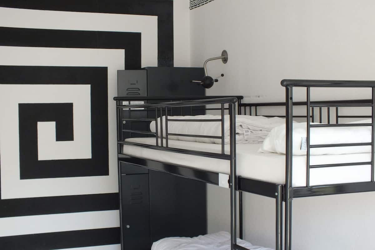 A bunk bed room with a geometric wall design, a small desk, and a mirror.