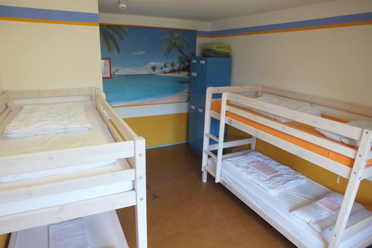 A room with bunk beds, a mural of a beach scene, and a blue cabinet.