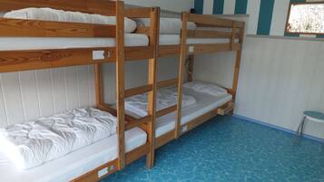 Ein Schlafzimmer mit Etagenbetten, einer gestreiften Wand und einem kleinen Hocker.