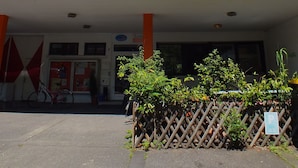 A building with a flat roof, large windows, and a covered entrance area with a sign that reads "Hostel."