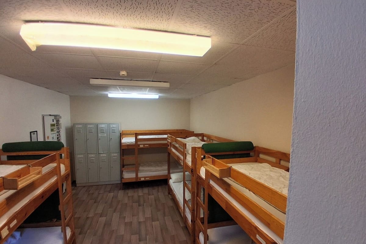 A dormitory room with bunk beds, a wardrobe, and lockers.