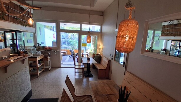 A cozy cafe with wooden furniture, a large window, and a hanging light fixture.