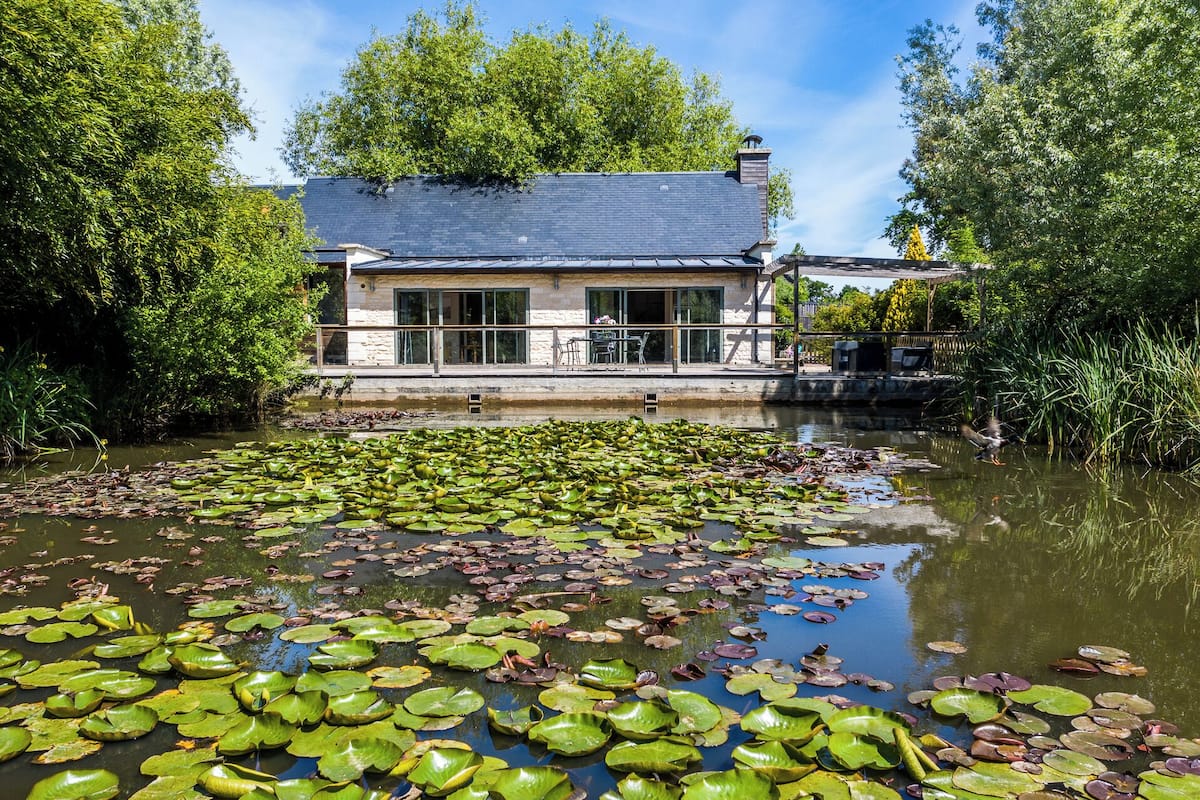 A building with a large windowed front, a balcony, and a pond with lily pads.