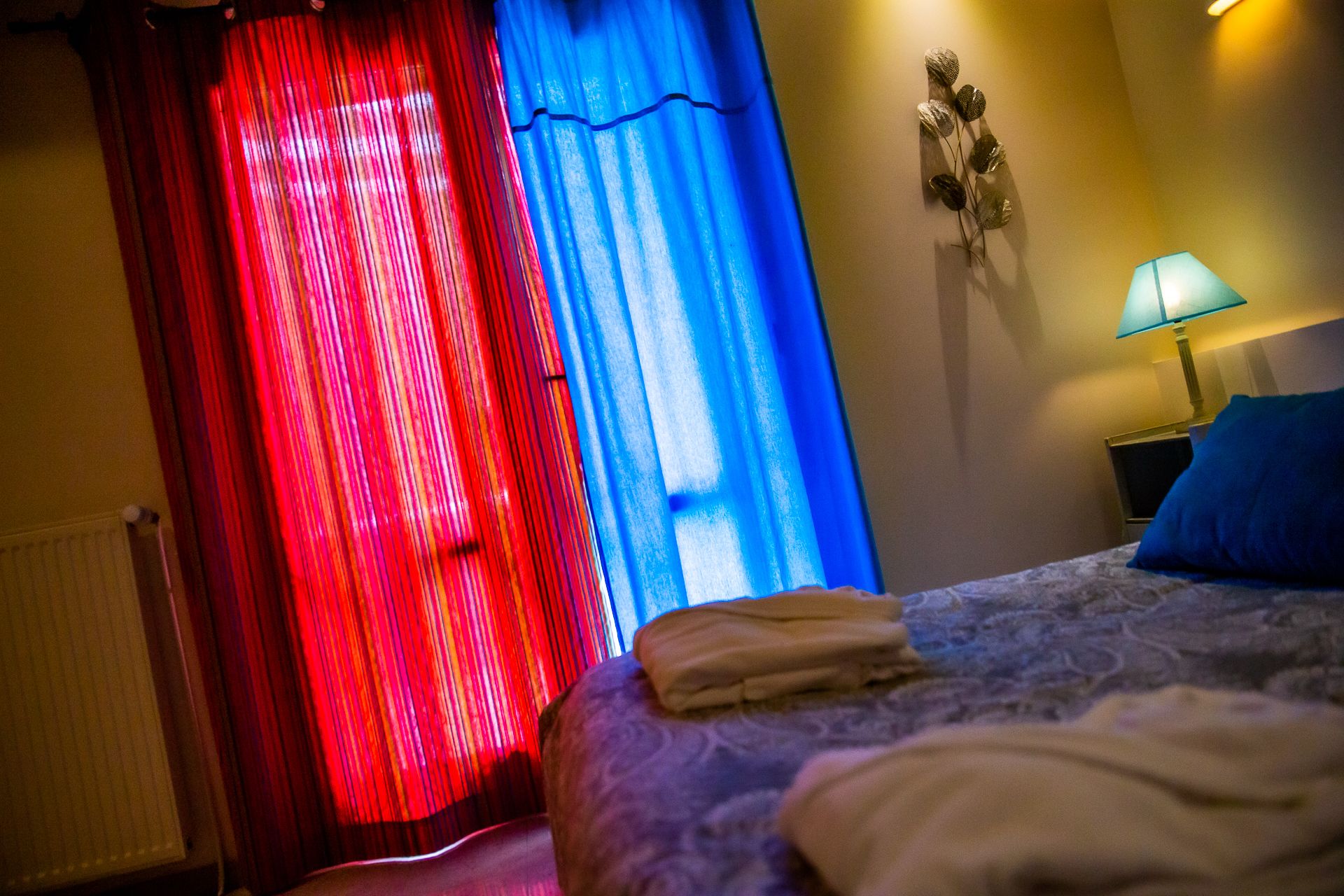 Une chambre d’hôtel avec un lit, une table de chevet, une lampe et des rideaux.