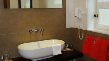 A bathroom with a large white sink, a mirror above it, and a red towel hanging on the wall.