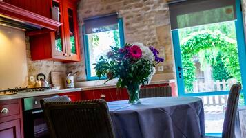 A kitchen with red cabinets, a gas stove, and a dining area with a table and chairs.