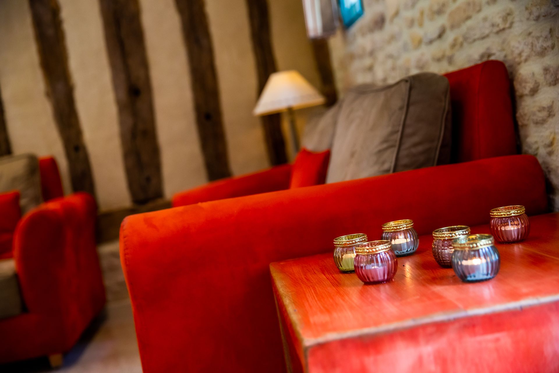 Um sofá vermelho com uma pequena mesa na frente, exibindo vários frascos decorativos.