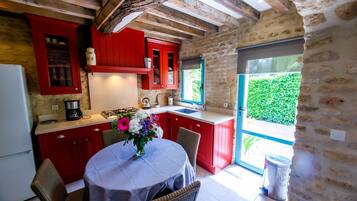 A kitchen with red cabinets, a gas stove, and a dining area with a table and chairs.