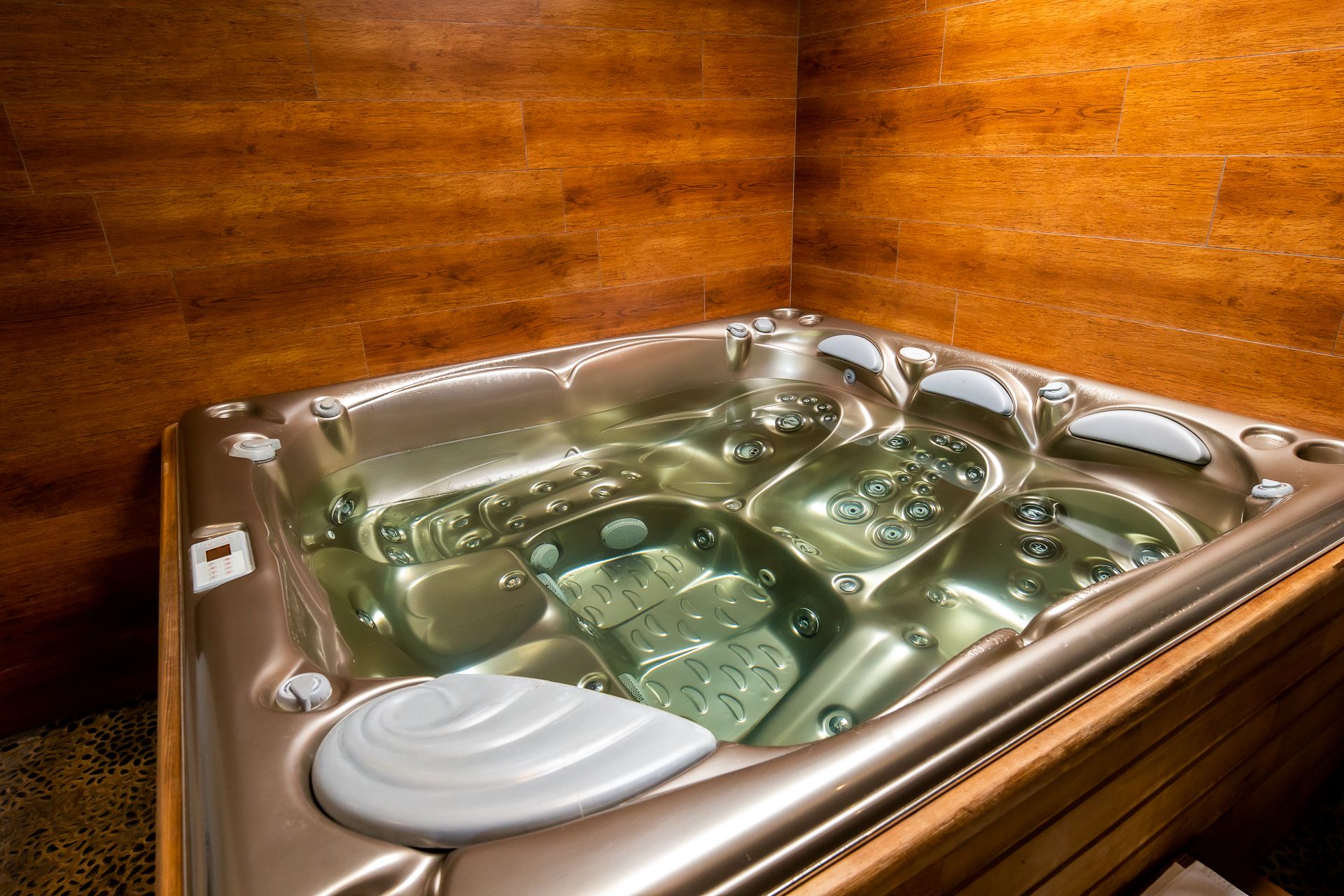 A hot tub with multiple jets, a control panel, and a footrest.
