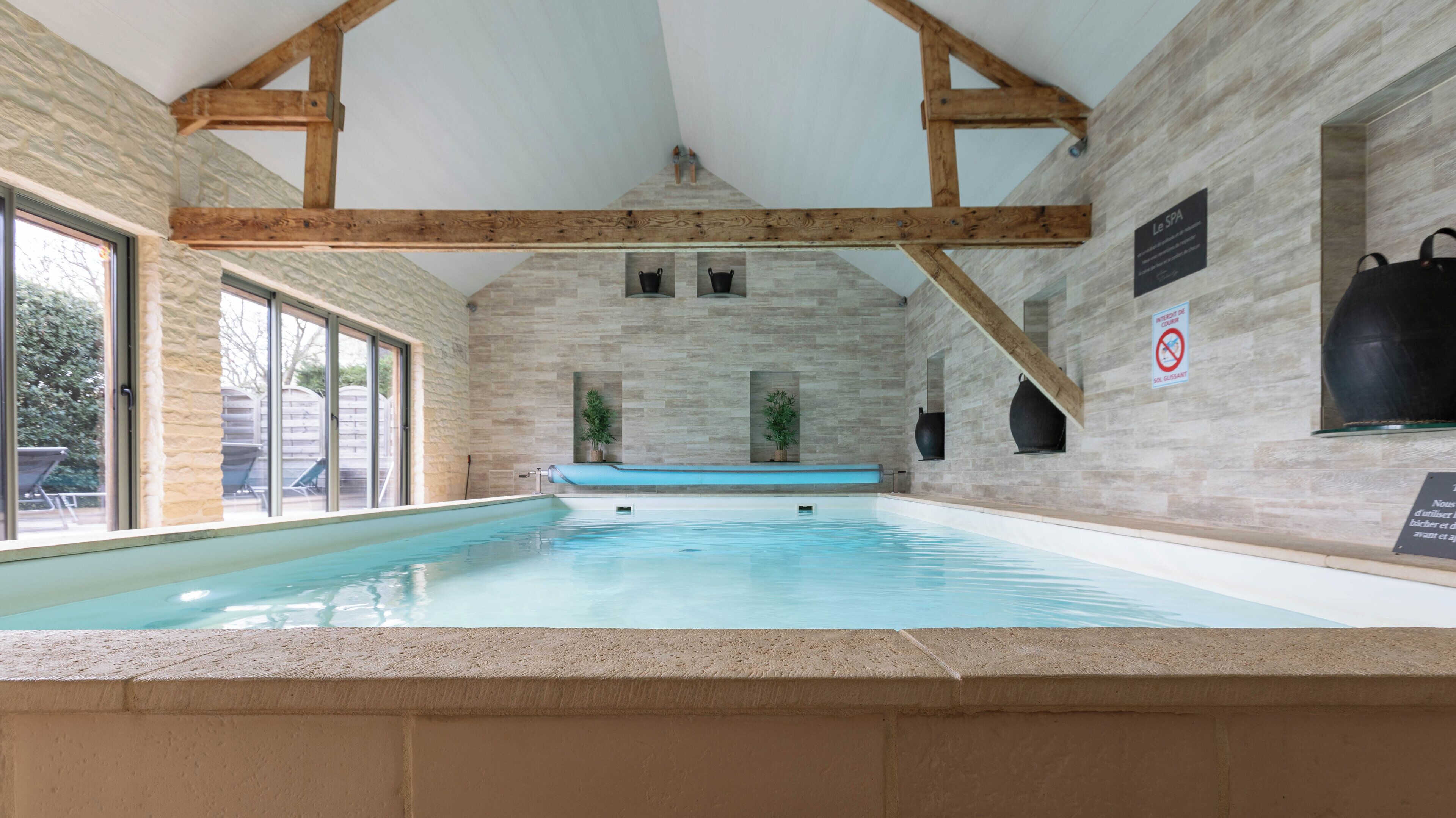 An indoor swimming pool with stone walls and wooden beams.