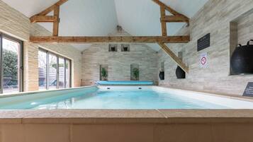 An indoor swimming pool with stone walls and wooden beams.
