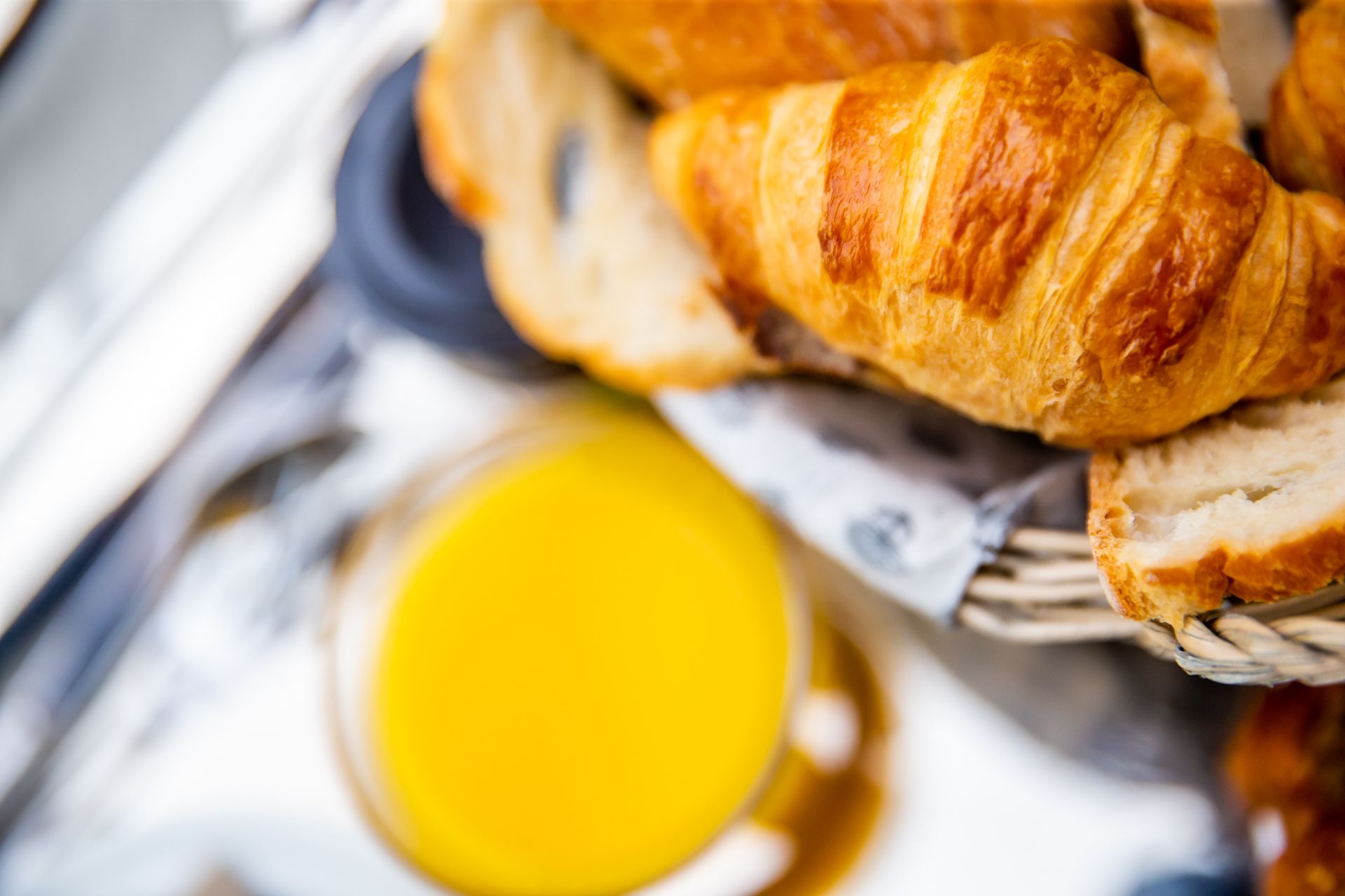 A basket containing croissants and a glass of orange juice.