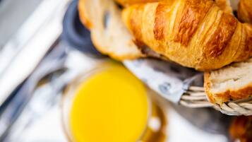 A basket containing croissants and a glass of orange juice.