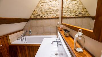 A bathroom with a wooden vanity, a bathtub, and a stone wall.