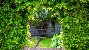 A wooden fence with a garden area in front. - Maison d'Hôtes La Ferme de L'Oudon & Spa (Saint-Pierre-en-Auge)