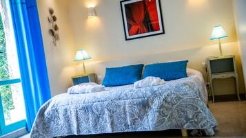 Un letto rifatto con una coperta a motivi, due cuscini blu e due lampade da comodino.