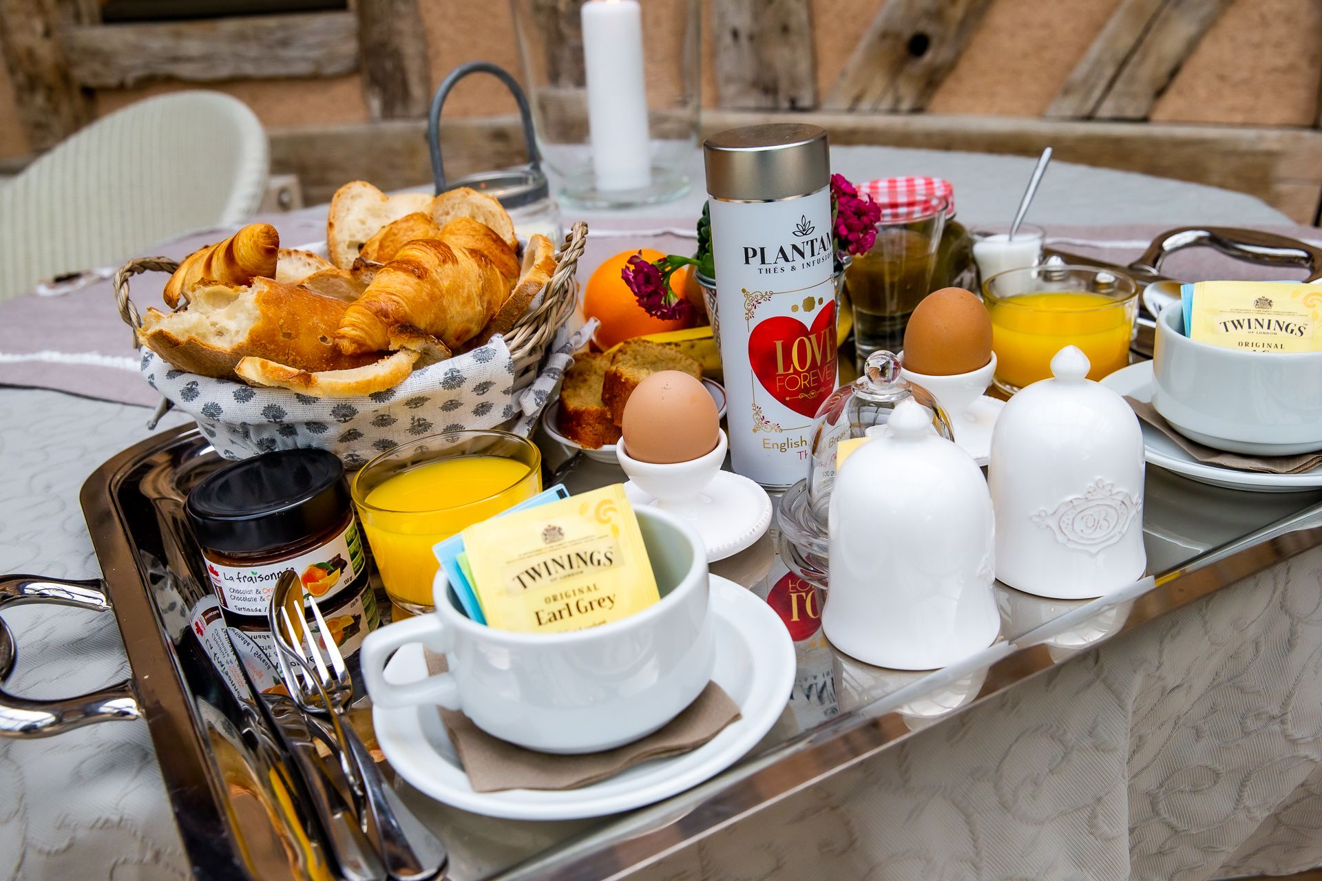 Bandeja de desayuno con cruasanes, huevos, jugo de naranja y té Earl Grey Twinings.