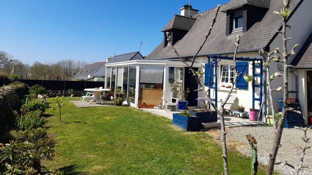 A house with a conservatory, a garden, and a patio area with outdoor furniture. - Chambres d'hôtes Maison Entre Terre et Mer (Primelin)