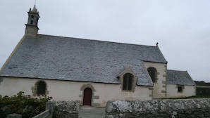 A small stone church with a red door and a tiled roof. - Chambres d'hôtes Maison Entre Terre et Mer (Primelin)