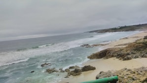 A coastal view with a sandy beach, rocky shoreline, and a cloudy sky. - Chambres d'hôtes Maison Entre Terre et Mer (Primelin)
