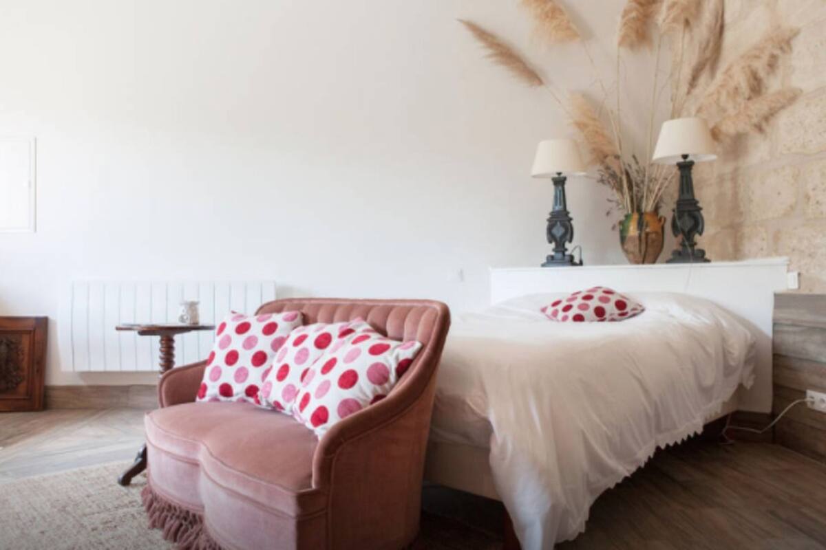 A bedroom with a bed, a chair, a nightstand, and a lamp.