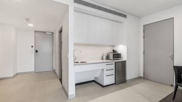A modern kitchen with white cabinets, a microwave, and a sink.