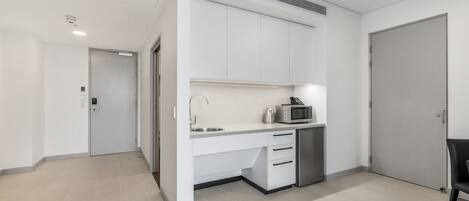 A modern kitchen with white cabinets, a microwave, and a sink.