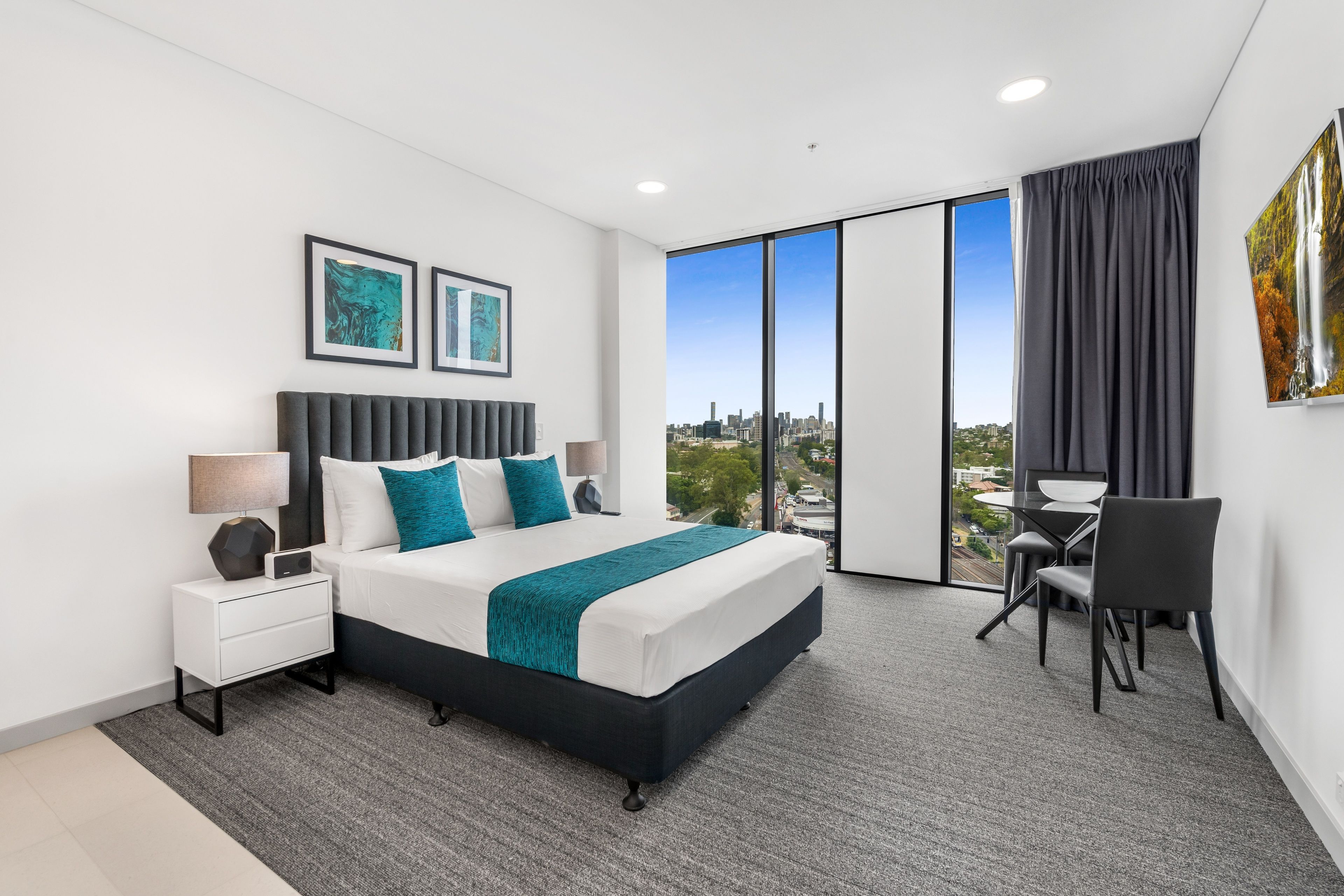Ein modernes Hotelzimmer mit einem großen Bett, einem Schreibtisch und Blick auf die Stadt.