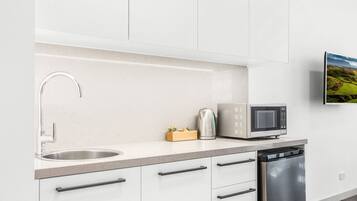 A modern kitchen with white cabinets, a stainless steel sink, a microwave, and a dishwasher.