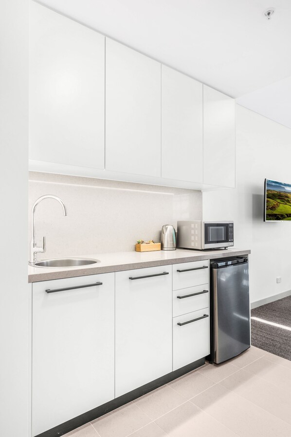 A modern kitchen with white cabinets, a stainless steel sink, a microwave, and a dishwasher.