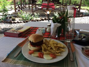 Una comida con hamburguesa, papas fritas y verduras sobre una mesa al aire libre.