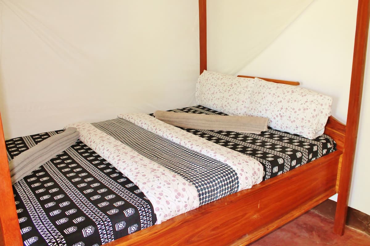 Una cama con dosel de madera con ropa de cama y almohadas estampadas.