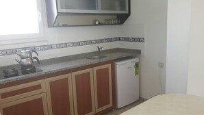 A kitchen with wooden cabinets, a white refrigerator, a sink, and a kettle on the countertop. - Jasmin Court Apart Otel (Silifke)
