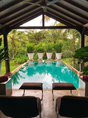 A covered pool area with two lounge chairs and potted plants. - Casa Heliconia (Mirigama)