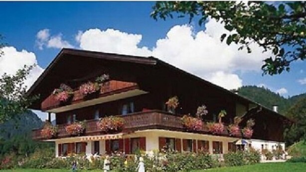A traditional chalet with a sloped roof, multiple balconies with flower boxes, and a well-maintained garden. - Liebertingerhof (Reit im Winkl)