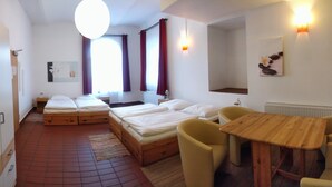 A hotel room with two beds, a wooden table, and a chair. - Picobello Pension (Görlitz)